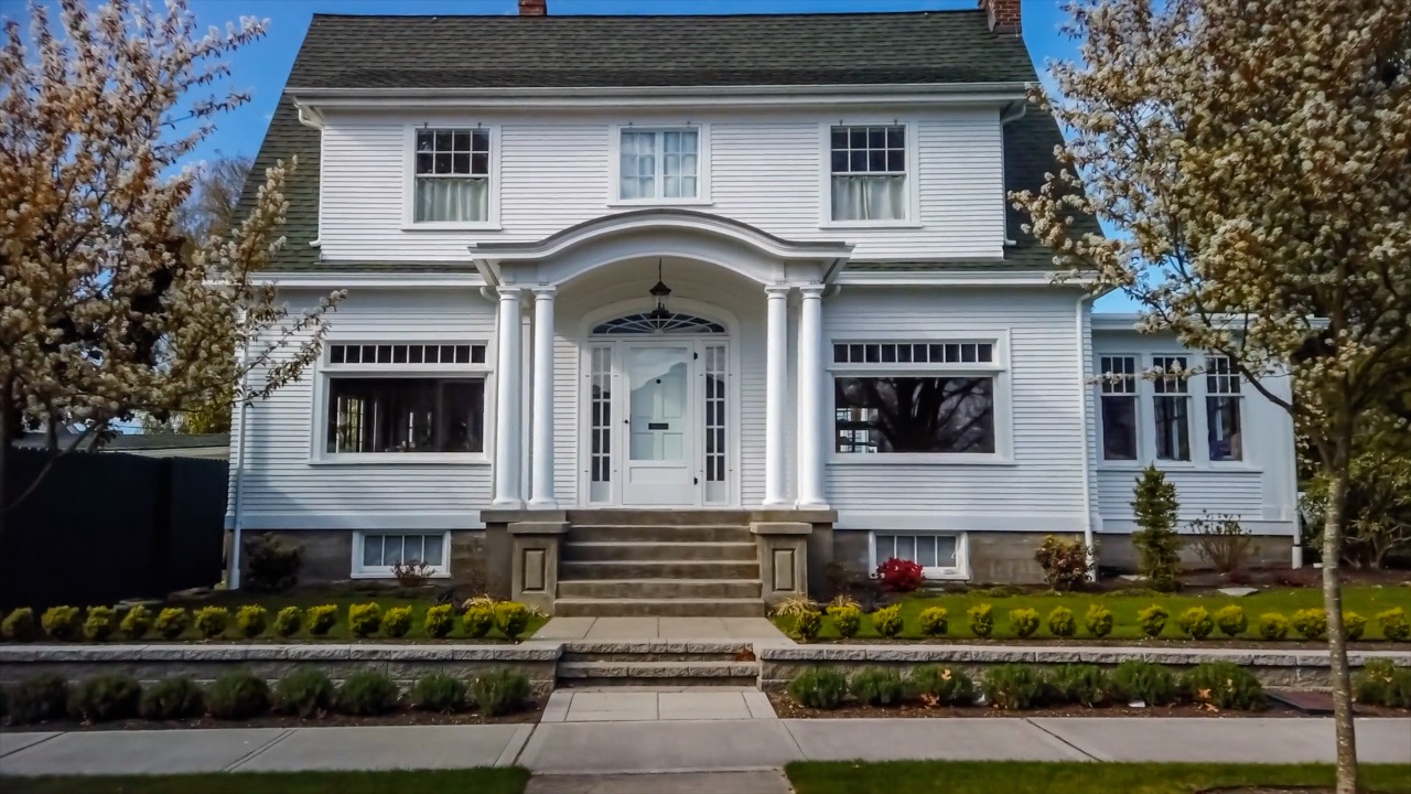 Stately home with steps leading to covered portico, trees on either side