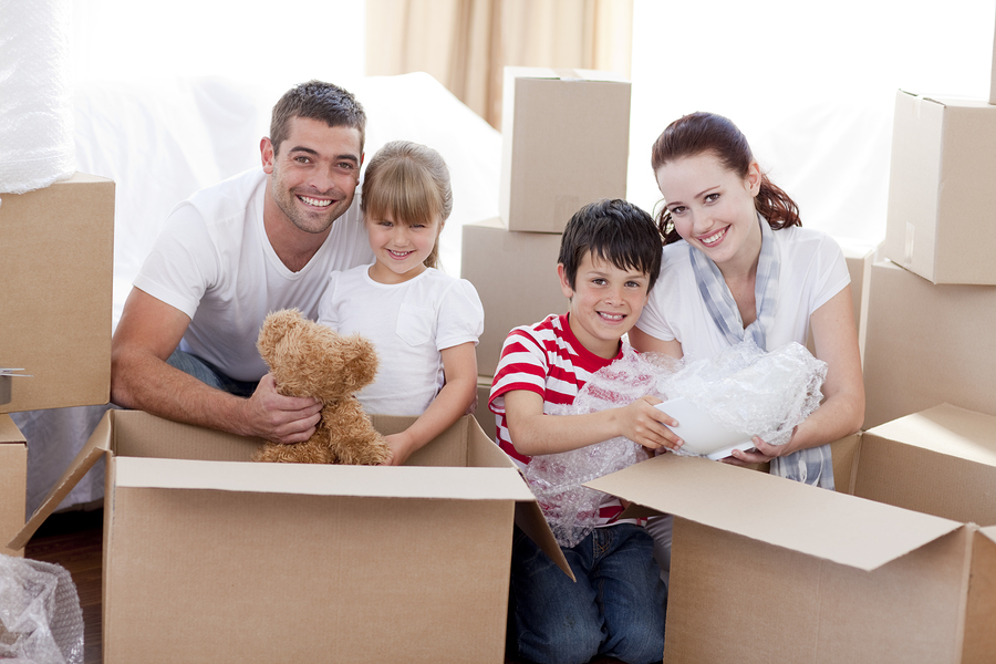 family of four surrounded by boxes, unpacking boxes